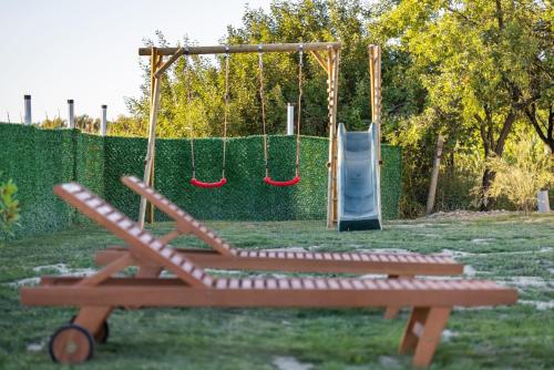 a playground with two swings and a slide at Ruralna kuća za odmor Bor Anya in Vardarac