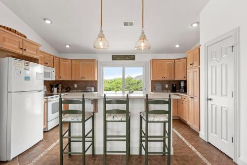 a kitchen with a white refrigerator and two bar stools at Rx To Relax in Duck