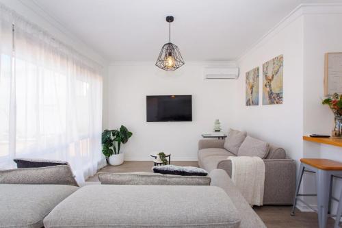 a living room with two couches and a tv at North Beach Nest - Walking Distance to North Beach in Perth