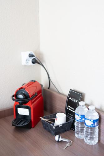 a table with a red toaster and bottles of water at Logis Hôtels et restaurant La Pause Rn7 in La Coucourde