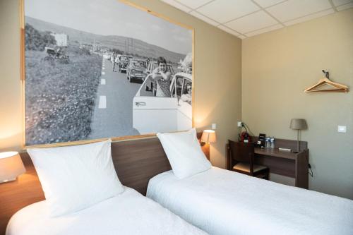 a hotel room with two beds and a picture on the wall at Logis Hôtels et restaurant La Pause Rn7 in La Coucourde