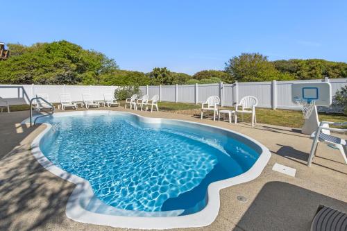a pool with chairs and a basketball hoop at Rx To Relax in Duck