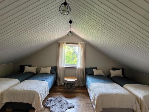 ein Zimmer mit drei Betten im Dachgeschoss mit Fenster in der Unterkunft Männisalu cozy houses with hot tube and many extras in Mägari