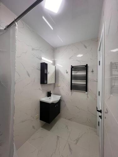 a white bathroom with a sink and a mirror at Comfort class apartment 10 in Kutaisi