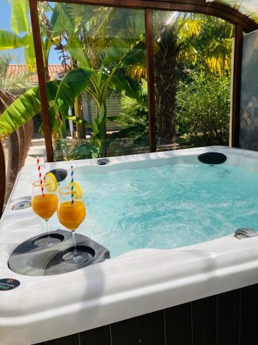 deux verres de jus d'orange assis sur un jacuzzi dans l'établissement Un petit bout de Louisiane chambre d'hôtes avec Piscine et Petit Déjeuner, à Chantonnay