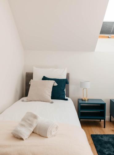 a bedroom with a white bed with a blue nightstand at Apartamenty Labuda in Garcz