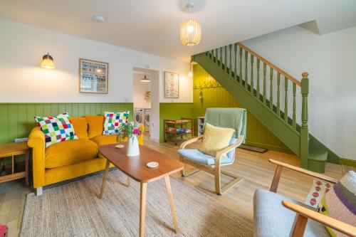 a living room with a yellow couch and a staircase at 4 Low Rake - Former Miners Cottage in Glenridding