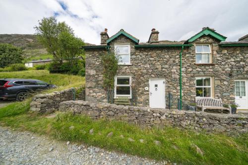 a stone house with a bench in front of it at 4 Low Rake - Former Miners Cottage in Glenridding