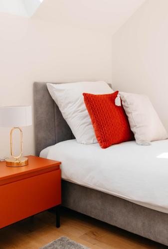 a bed with white and red pillows and a table at Apartamenty Labuda in Garcz