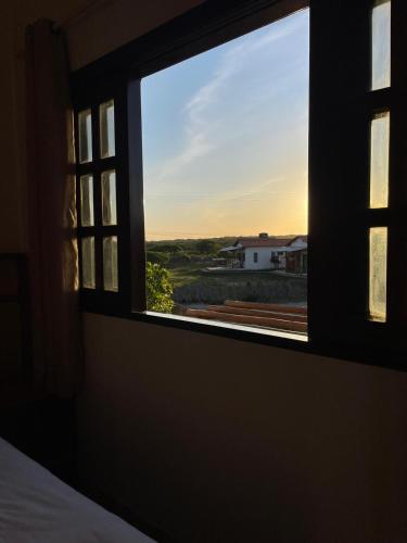 a bedroom window with a view of a house at Paraíso dos Lençóis casa 08 Atins in Atins