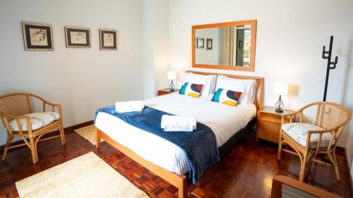 a bedroom with a bed with two chairs and a mirror at Starry View in Funchal