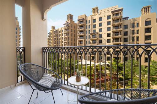 a balcony with two chairs and a table at Elegant Stay with Pool & Gym Near Iconic Landmarks in Dubai