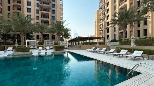 a swimming pool with white chairs and tables and buildings at Elegant Stay with Pool & Gym Near Iconic Landmarks in Dubai