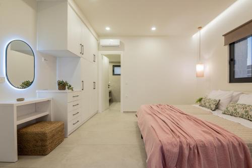 a white bedroom with a large bed and a mirror at Petra Natura Villa in Zakynthos Town