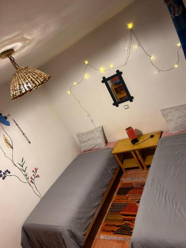 a bedroom with two beds and a table and lights at Tigmi Blue - Imsouane Surf et Océan in Imsouane