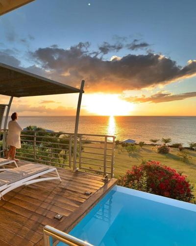 a woman standing on a deck watching the sunset at Blue Haven Villa 1 in Bouillante