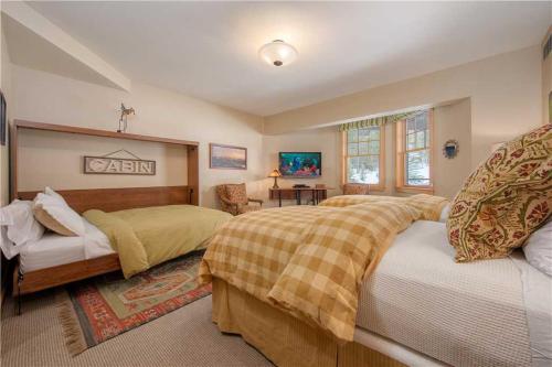 a bedroom with two beds and a chair and a table at RMR: Cody House B Condo in Teton Village in Teton Village