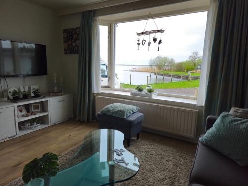 a living room with a large window with a view at Liefdevol chalet aan het meer in Suameer