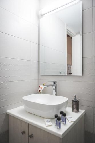 a white bathroom with a sink and a mirror at Elite luxury Suites in Omodos