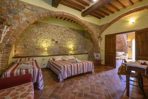 a bedroom with two beds and a stone wall at La Landuccia in Libbiano