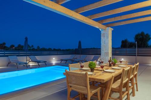 a dining area with a table and chairs next to a swimming pool at Petra Natura Villa in Zakynthos Town