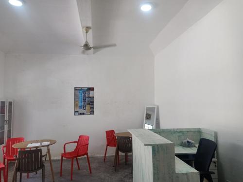 a room with red chairs and tables and a white wall at Fins Dive and Leisure Hotel in Rasdu