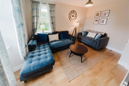 a living room with two blue couches and a table at Blairmore House in Broadford
