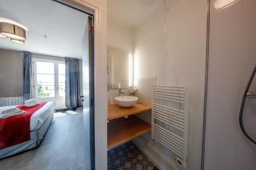 a bathroom with a bed and a sink in a room at Domaine de Presle Saumur, The Originals Relais in Distré