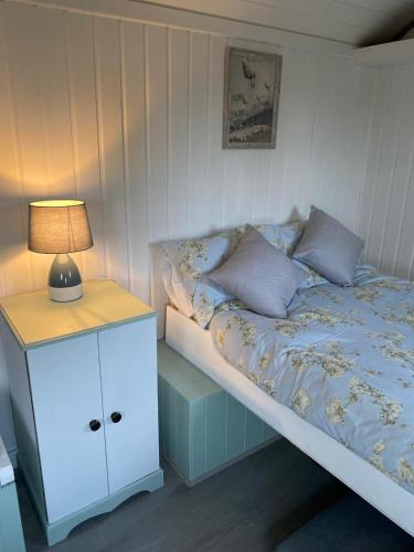 a bed with a nightstand and a lamp on it at Crabmill glamping bewdley in Bewdley