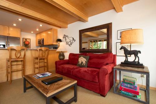 a living room with a red couch and a table at RMR: La Choumine 8 Condo in Teton Village in Teton Village
