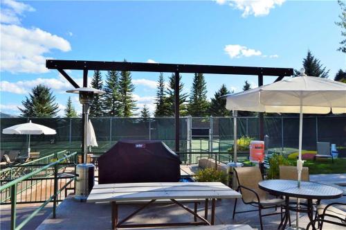 a patio with tables and umbrellas on a tennis court at RMR: La Choumine 8 Condo in Teton Village in Teton Village