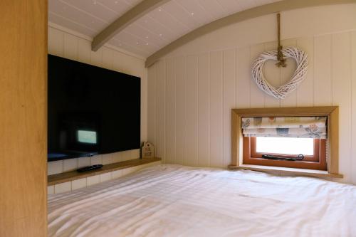 a bedroom with a bed and a flat screen tv at Bonnie's Shepherd's Hut - Wellness & Hot Tub in Nottingham