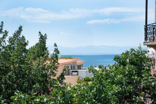a building with trees and the ocean in the background at Nely's Home in Aegina Town