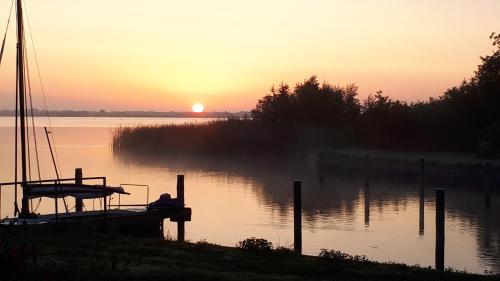 a boat sitting on the water at sunset at Liefdevol chalet aan het meer in Suameer