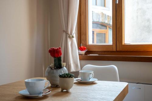 a table with two cups and a vase with flowers at Suites DANICA in Šmartno