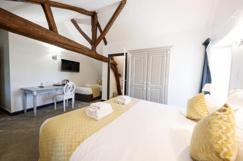 a bedroom with a bed and a desk in a room at Domaine de Presle Saumur, The Originals Relais in Distré