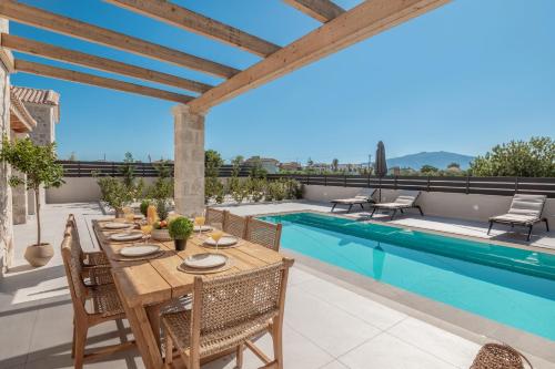 a patio with a table and chairs next to a swimming pool at Petra Natura Villa in Zakynthos Town