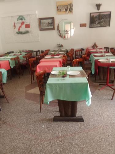 a dining room with red and green tables and chairs at Hôtel des cedres azrou in Oulad Akkou