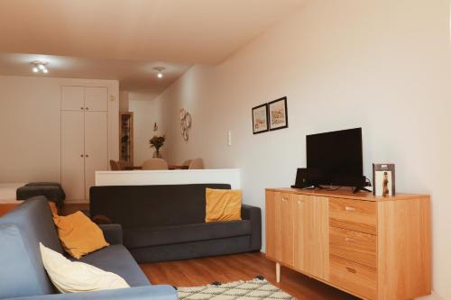 a living room with a couch and a tv on a wooden dresser at Casinha da Praia - Vila Nova de Gaia in Vila Nova de Gaia