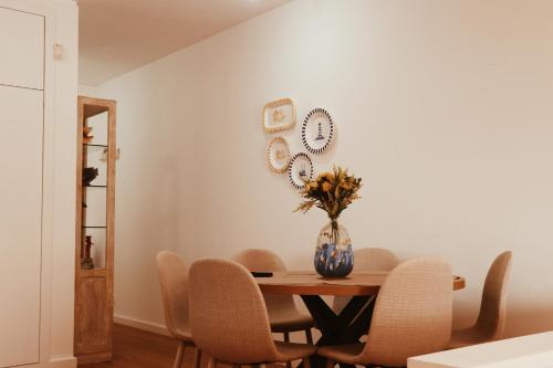 a dining room table with chairs and a vase with flowers at Casinha da Praia - Vila Nova de Gaia in Vila Nova de Gaia