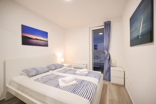 a white bedroom with a bed and a window at Villa Miri III in Privlaka