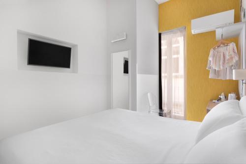 a white bedroom with a white bed and a tv at Palazzo Tasso in Sorrento