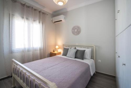 a white bedroom with a bed and a window at Nely's Home in Aegina Town