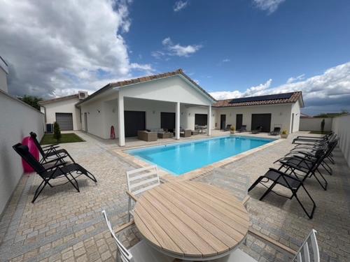 une piscine avec des chaises et une table en bois et une table et des chaises dans l'établissement Les Crechois, à Crêches-sur-Saône