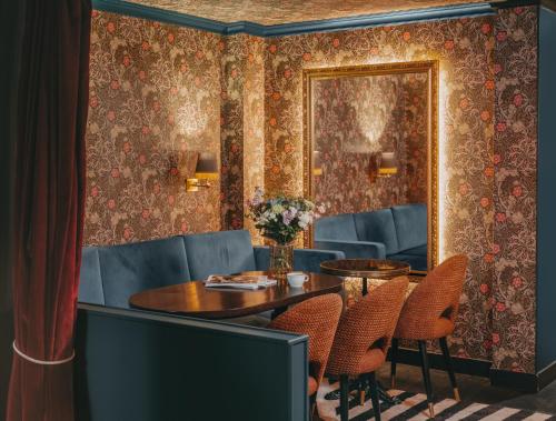 une salle à manger avec une table, des chaises et un miroir dans l'établissement Snob Hotel, à Paris