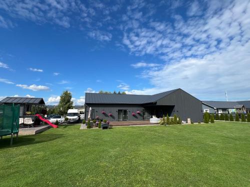 a large building with a grass field in front of it at Männi Villa in Haaslava