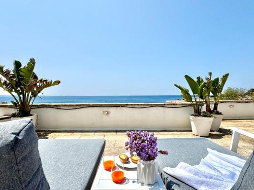 a table with fruit and flowers on a balcony with the ocean at Villa Nauna, fronte mare con giardino e terrazzo - Marea Stays Collection in Nardò
