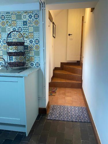 a hallway with a tile wall and a staircase at Village Cottage 5 minutes to Alton Towers in Alton