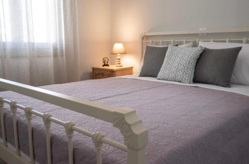 a bedroom with a bed with a purple blanket and a window at Nely's Home in Aegina Town