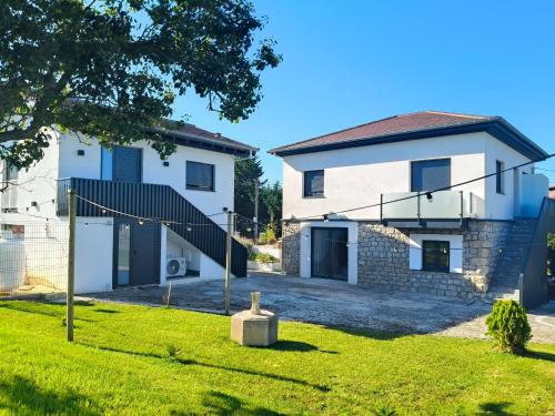 a white house with a gate and a yard at Apartamentos la Leyenda in Santillana del Mar
